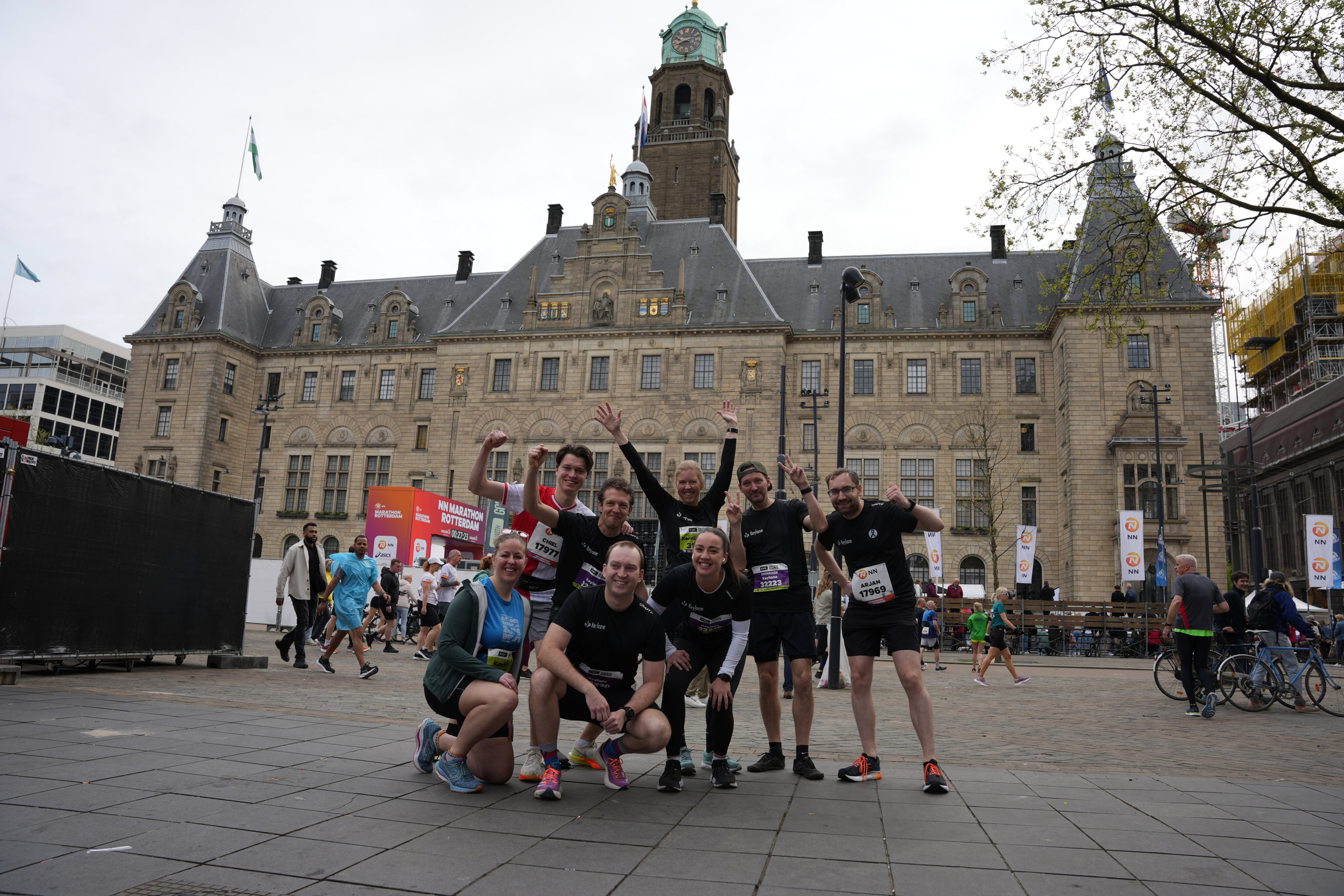 Active group of marathon runners celebrating in front of historic city hall during a corporate team-building event.