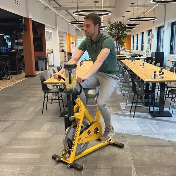 1. Young man riding a stationary exercise bike indoors at Keylane Careers office for a healthy and active work environment.